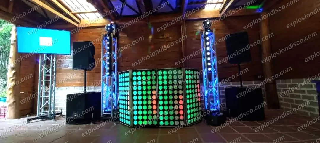 Cabina de DJ con panel LED, torres de luces, bocinas y pantalla en un salón de madera en Guatemala