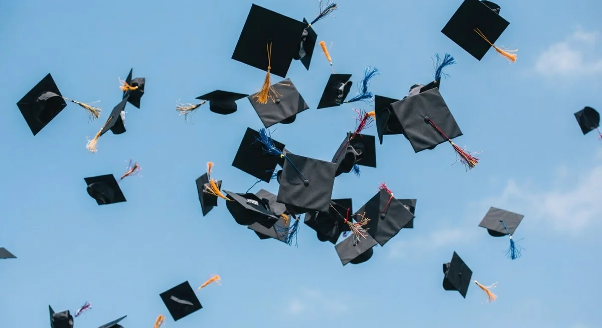 Birretes de graduación lanzados al aire contra un cielo azul