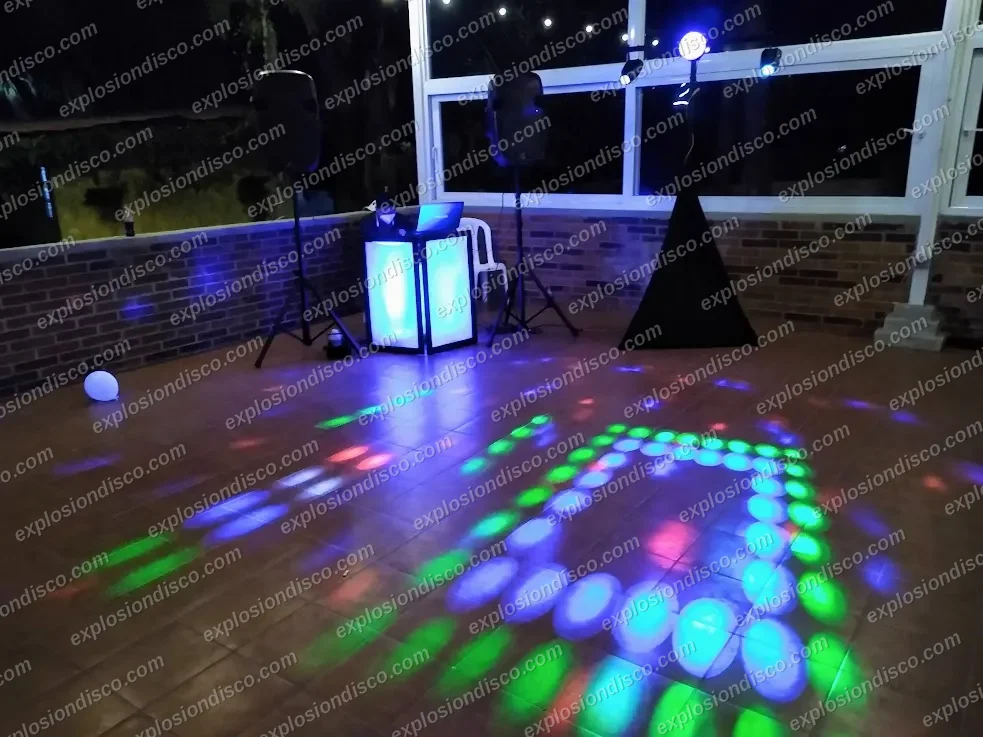 Cabina de DJ, bocinas y luces proyectando figuras de colores sobre la pista de baile de un salón en Guatemala